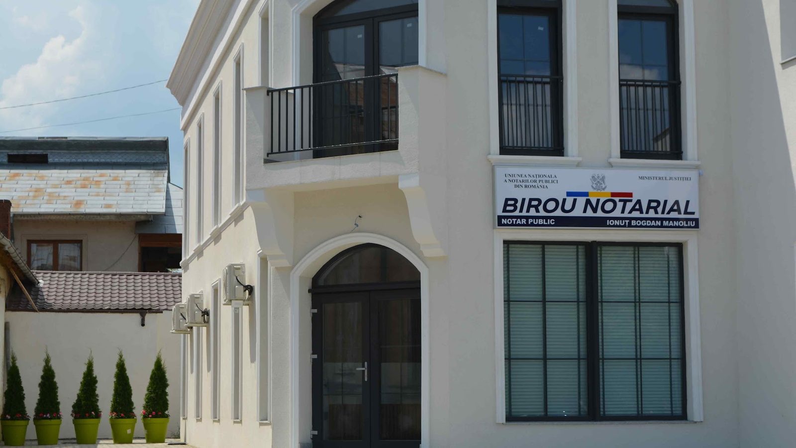 Intrarea în Biroul Notarial Ionuț-Bogdan Manoliu, cu firma Uniunii Naționale a Notarilor Publici montată pe fațadă.
